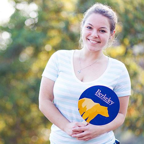 Female wearing striped shirt and holding a Berkeley fan with a golden bear